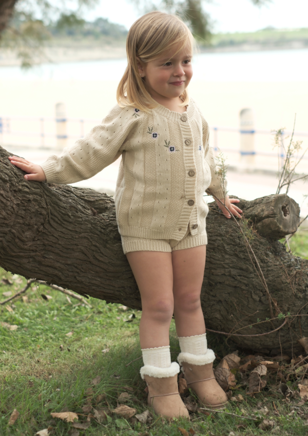 Cardigan para bebé en color vainilla natural con botones de madera, parte del set Tivoli